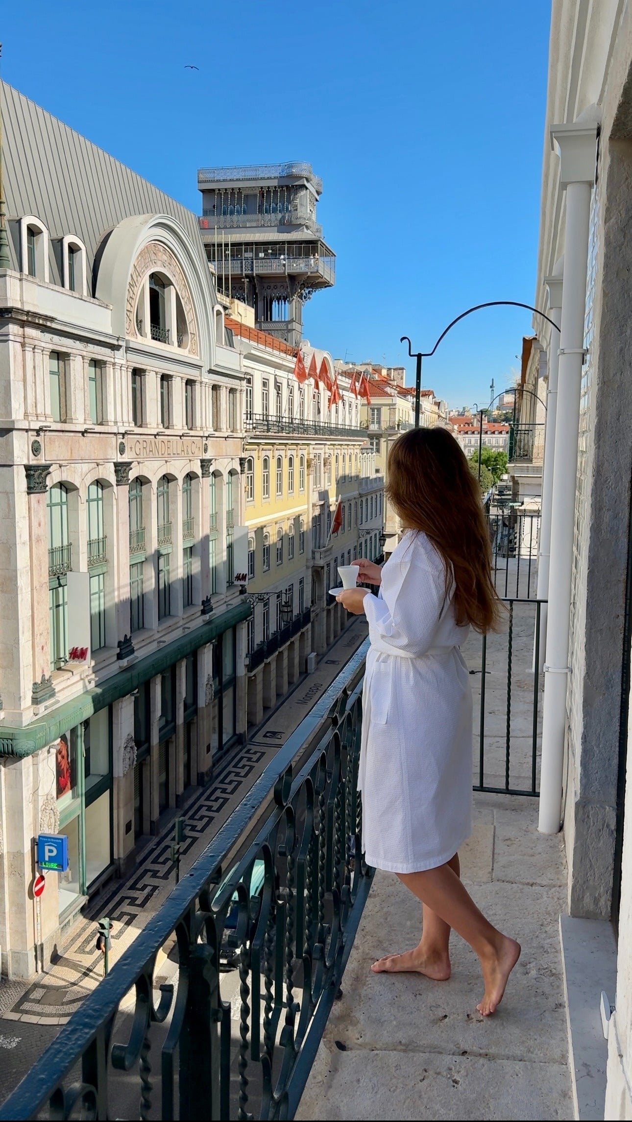 uma mulher está em uma varanda segurando uma xícara de café