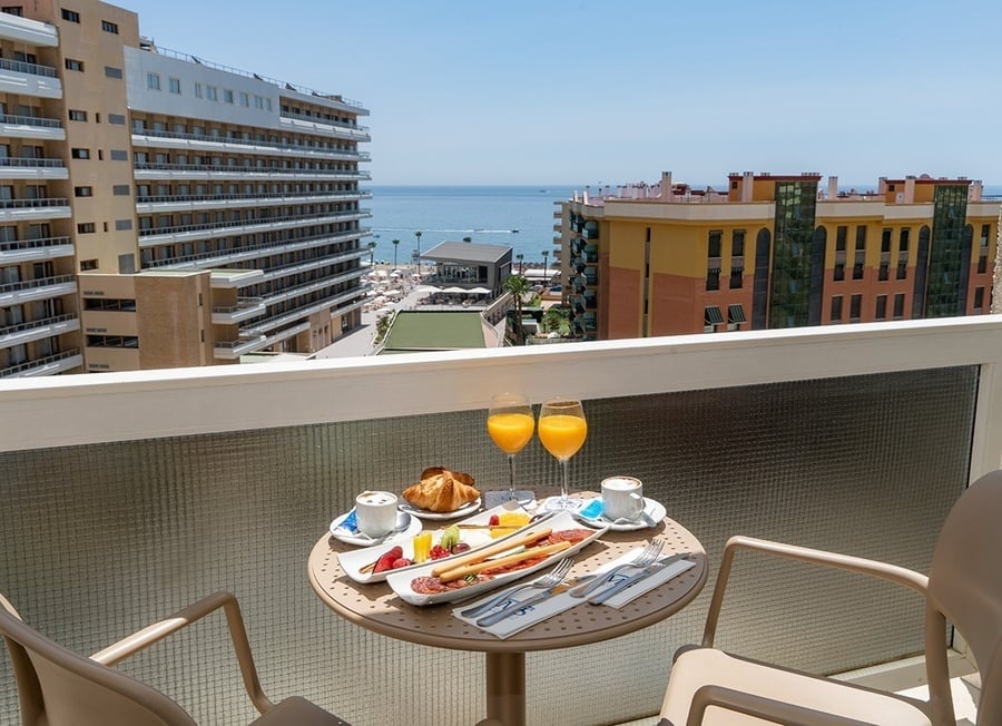 una mesa con comida y bebidas en un balcón con vistas al océano