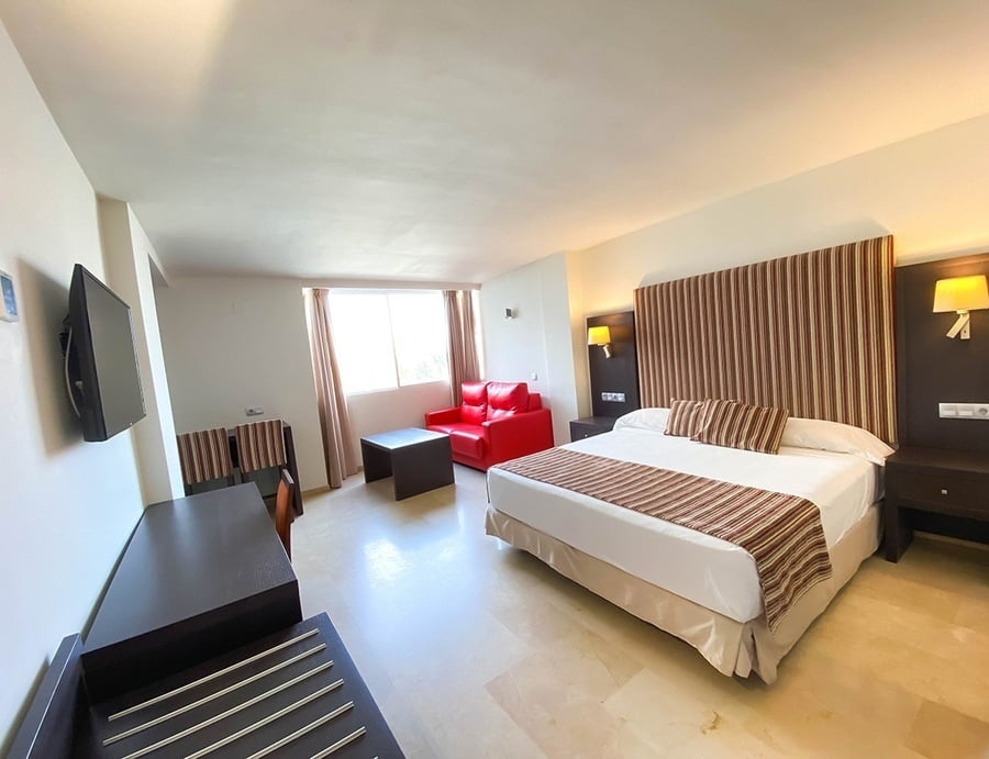 a hotel room with a large bed and a red chair