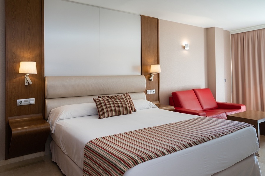 una habitación de hotel con una cama y un sofá rojo