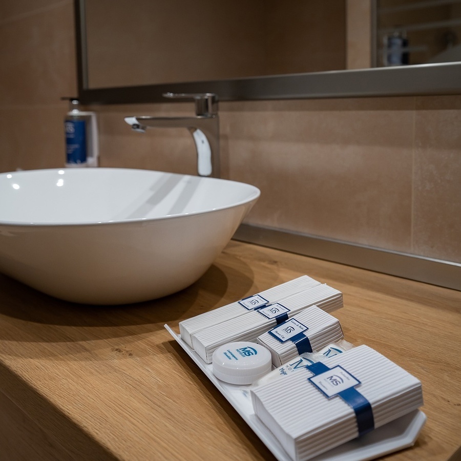 a bathroom counter with a sink and a tray of soaps and lotion