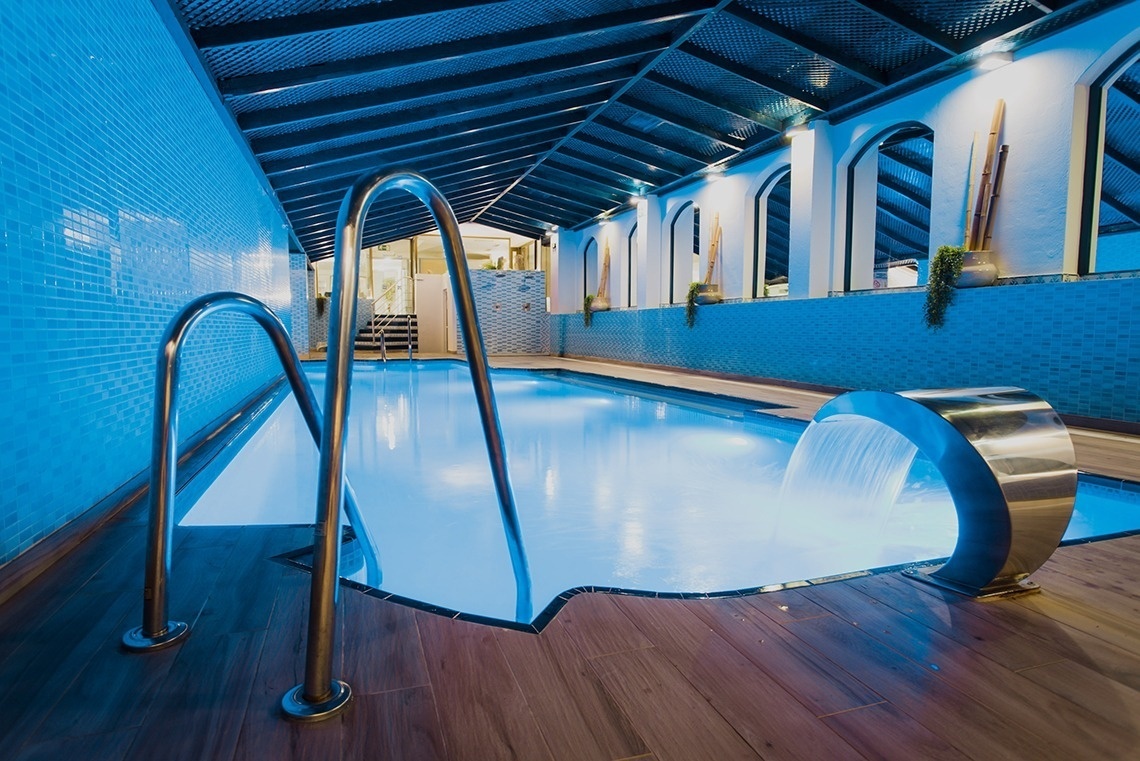 a swimming pool with blue tiles and a waterfall