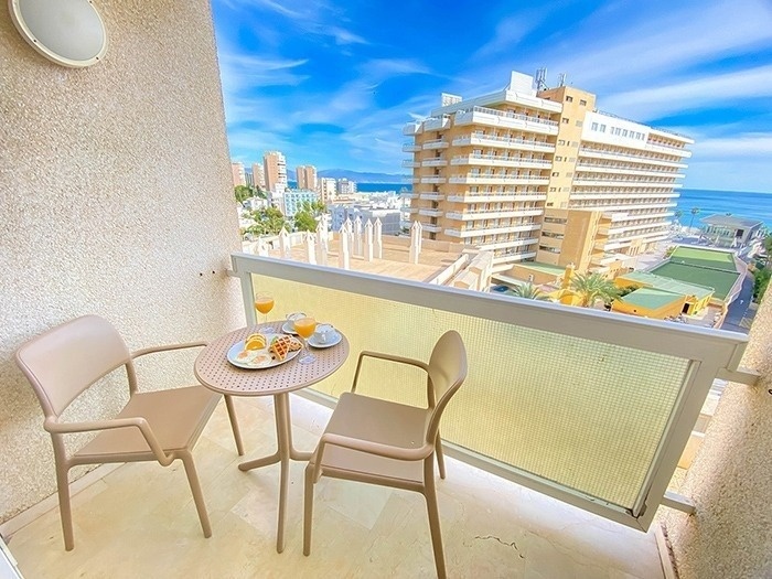 una mesa y sillas en un balcón con vista al océano