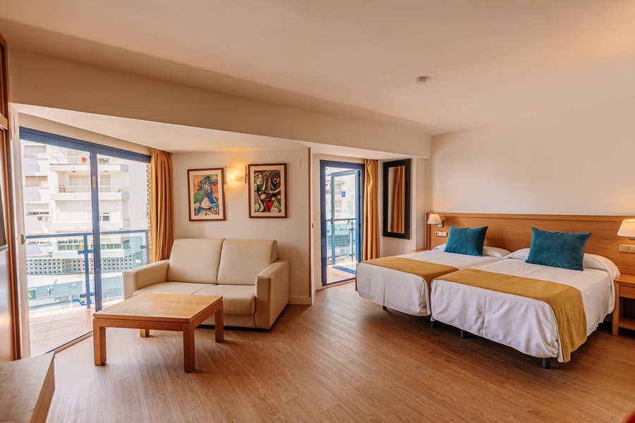 Amplia habitación de hotel con dos camas, sofá, mesa y balcón. MS hoteles: Puerto Marina en hotel moderno.