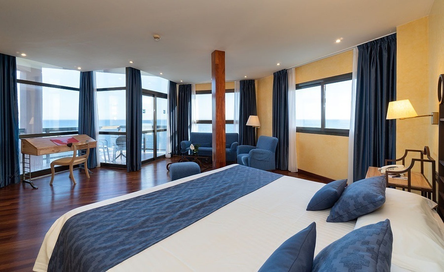 una habitación de hotel con una cama king size y muchas ventanas
