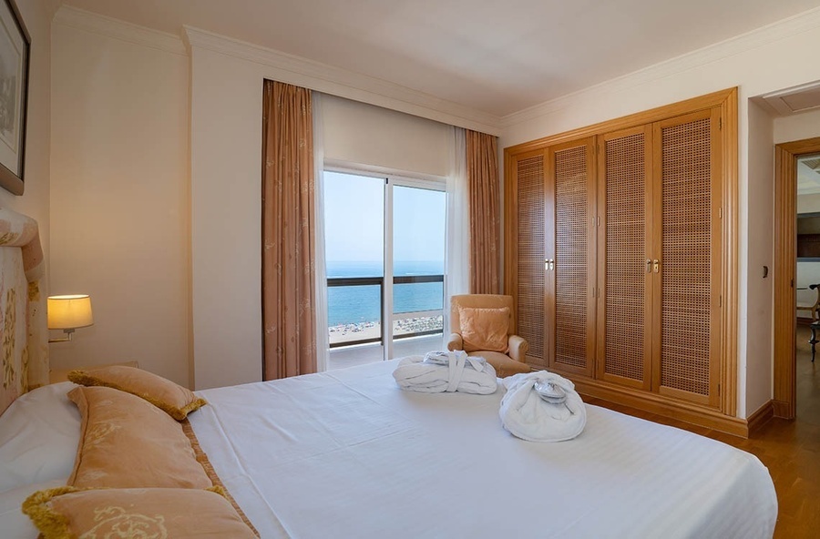 una cama y una silla en una habitación con vista al océano
