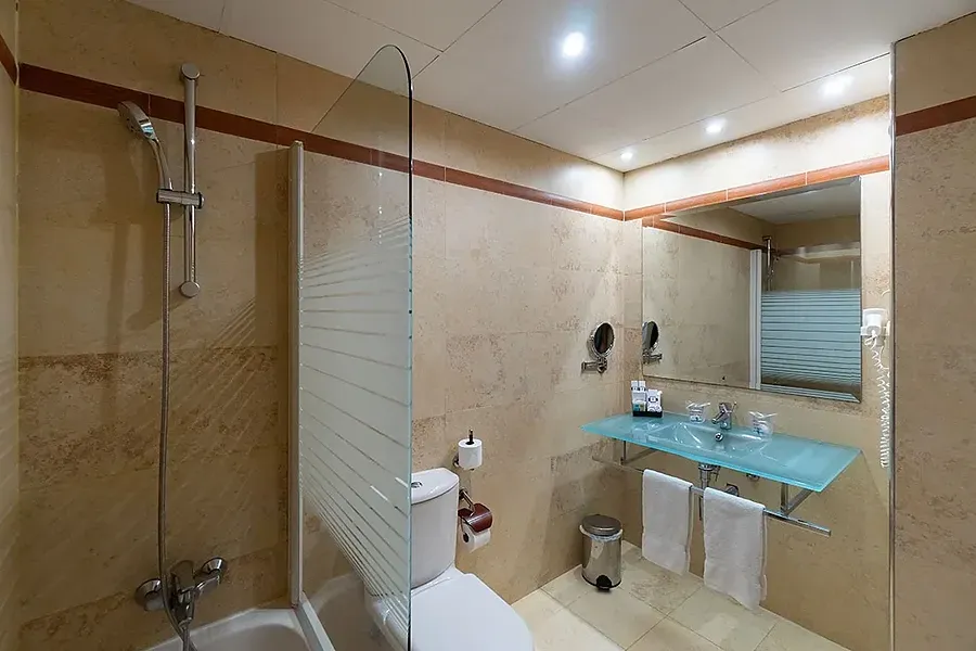 Baño moderno con ducha, inodoro y lavabo de cristal. MS: Maestranza