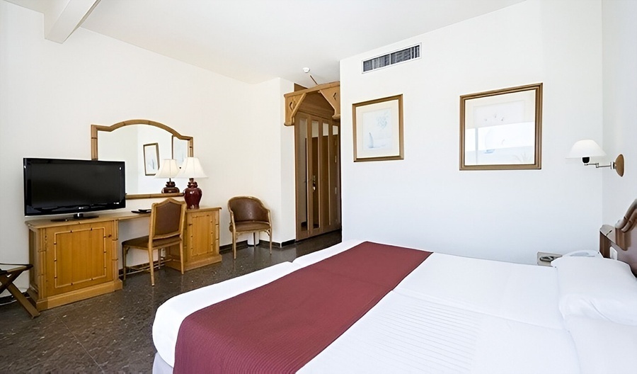 a hotel room with a bed a desk and a flat screen tv