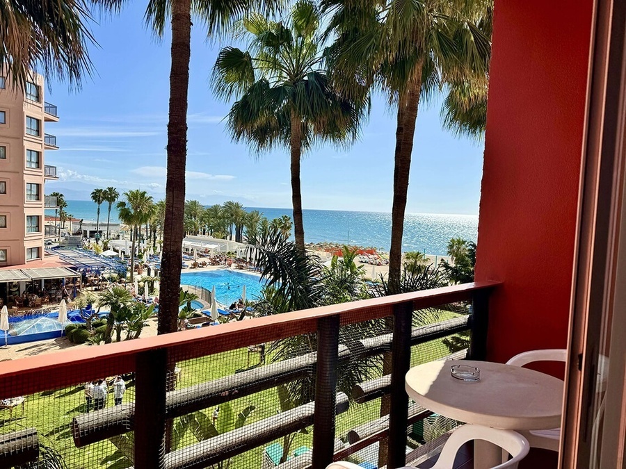 a balcony with a view of the ocean and palm trees