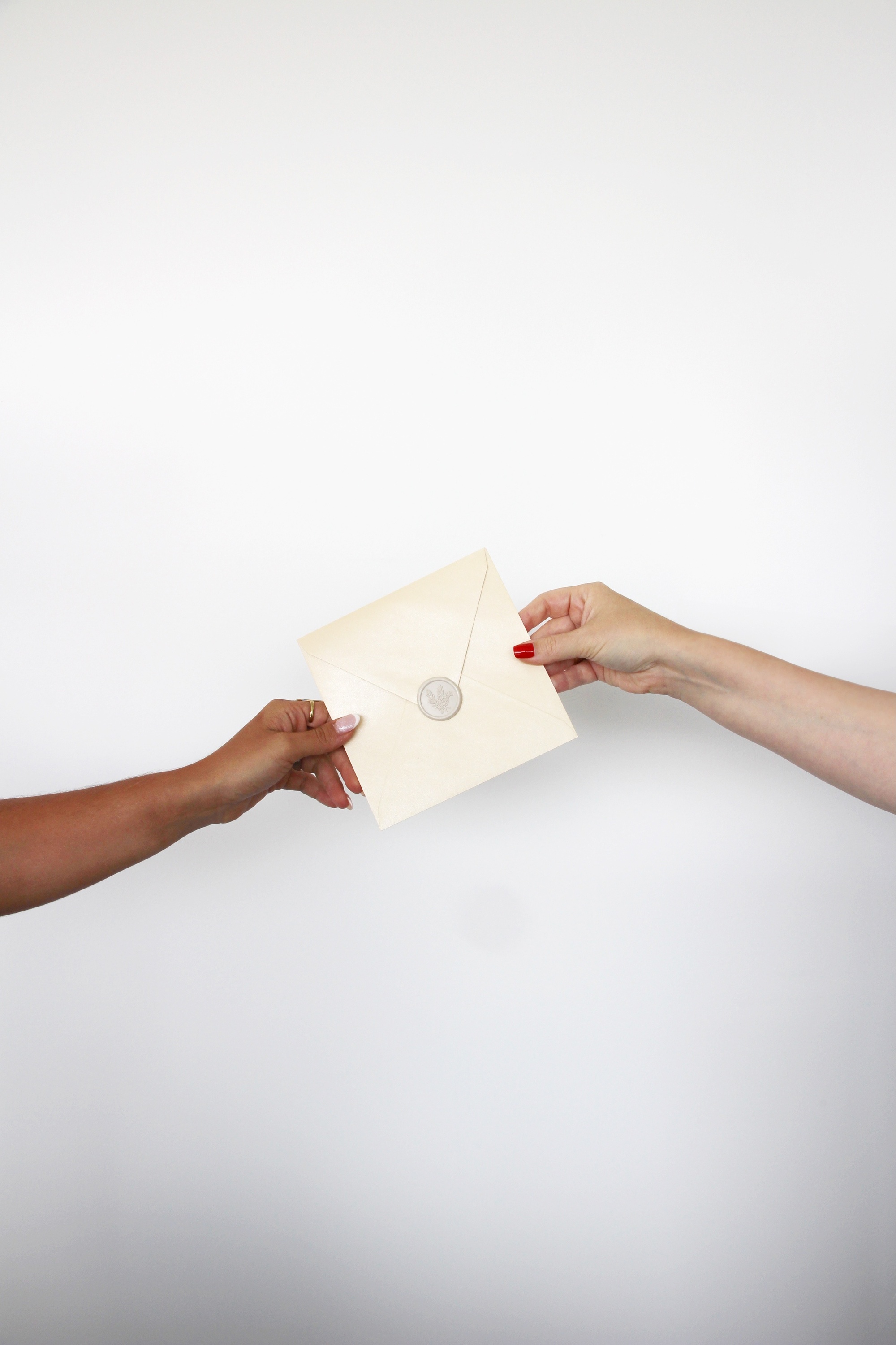 duas mãos estão segurando um envelope com um selo de cera