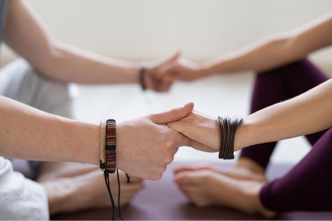 dos personas se toman de la mano con pulseras en sus muñecas