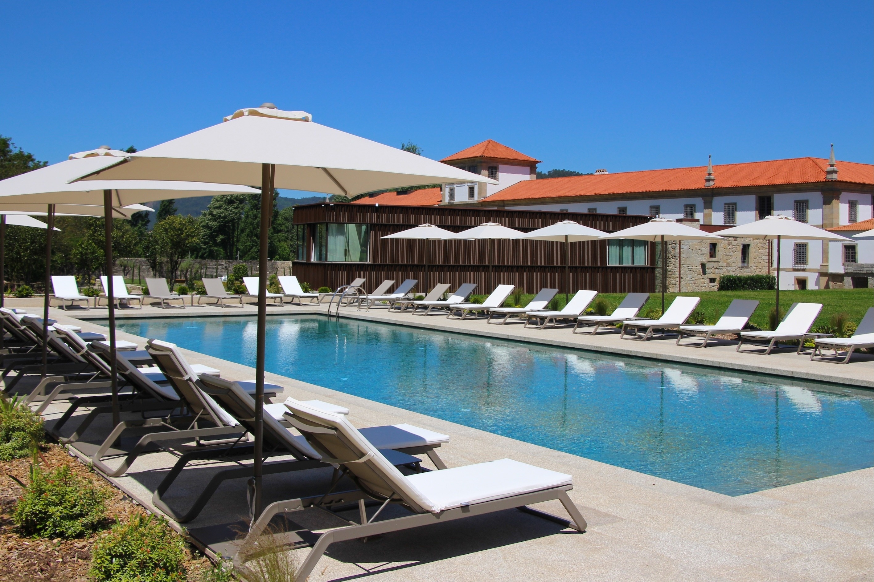 una piscina con sillas y sombrillas alrededor de ella