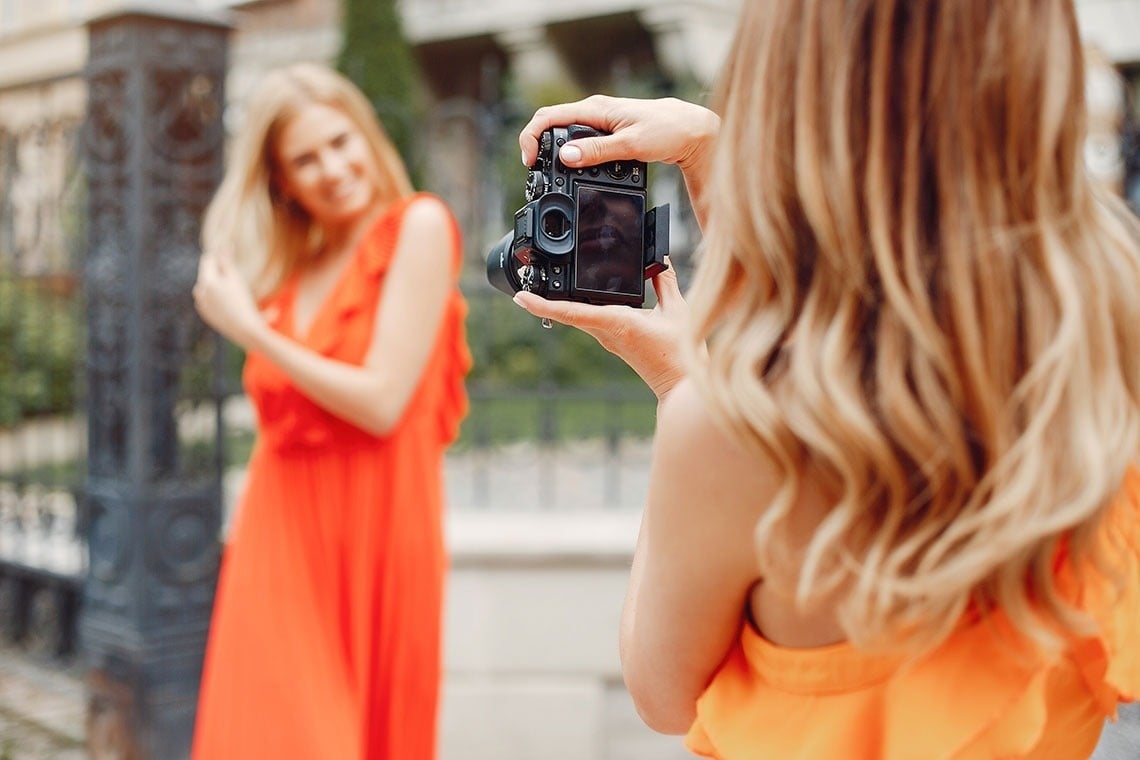 una mujer toma una foto de una mujer con un vestido naranja