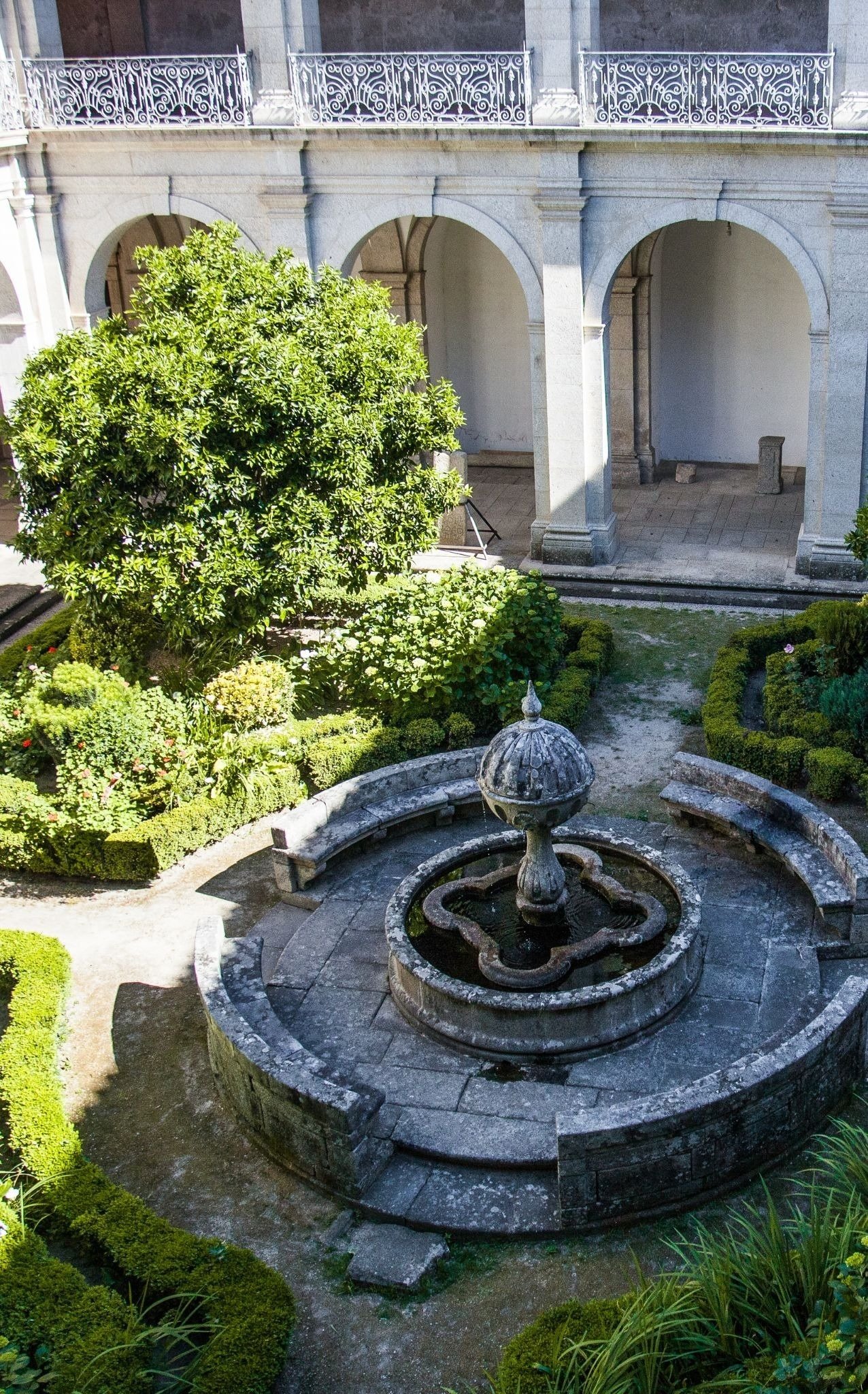 una fuente en un patio rodeado de árboles y arbustos