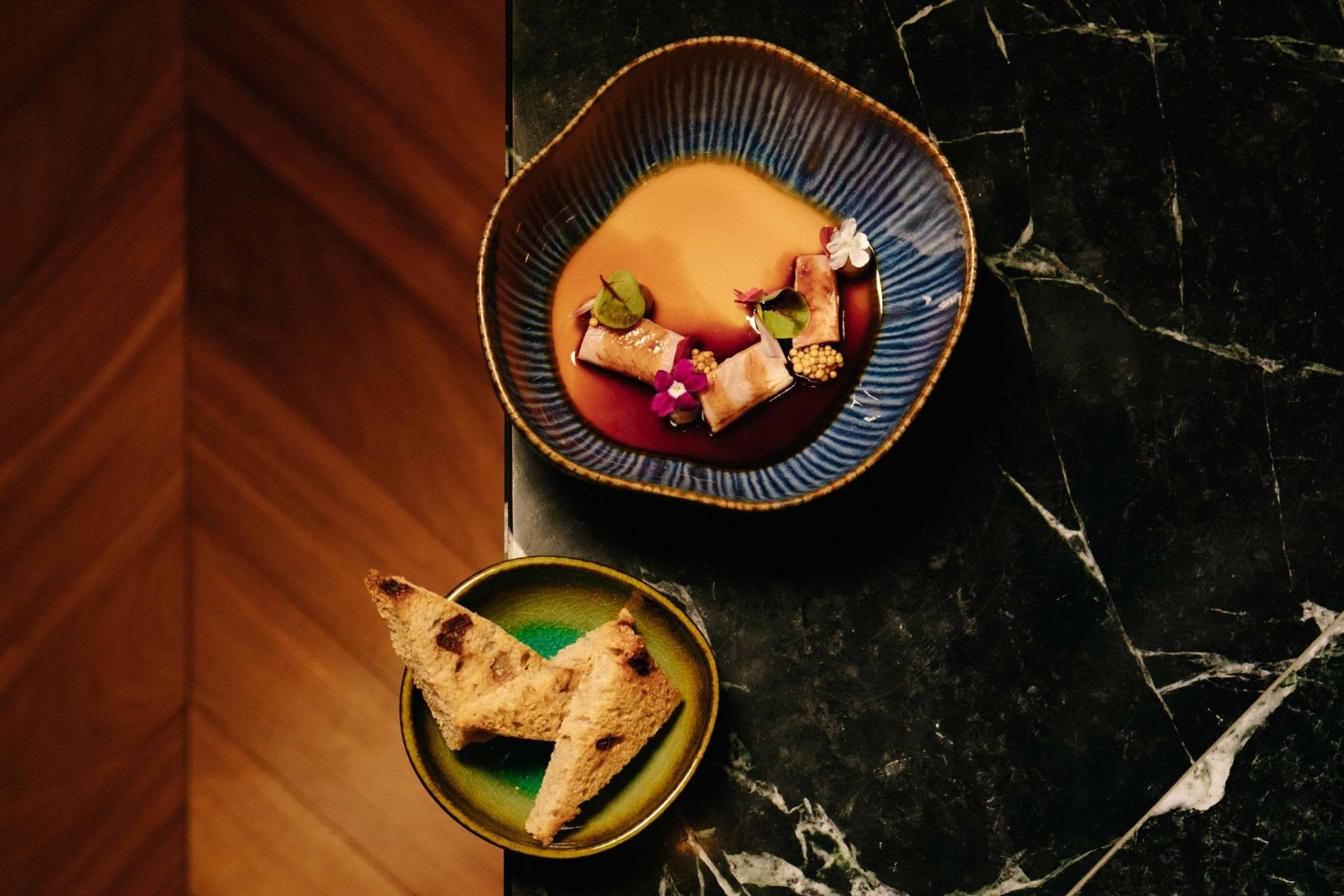 two bowls of food on a table including a slice of bread