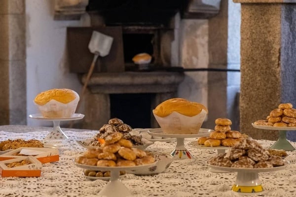 uma mesa cheia de doces com uma caixa de pão ao fundo