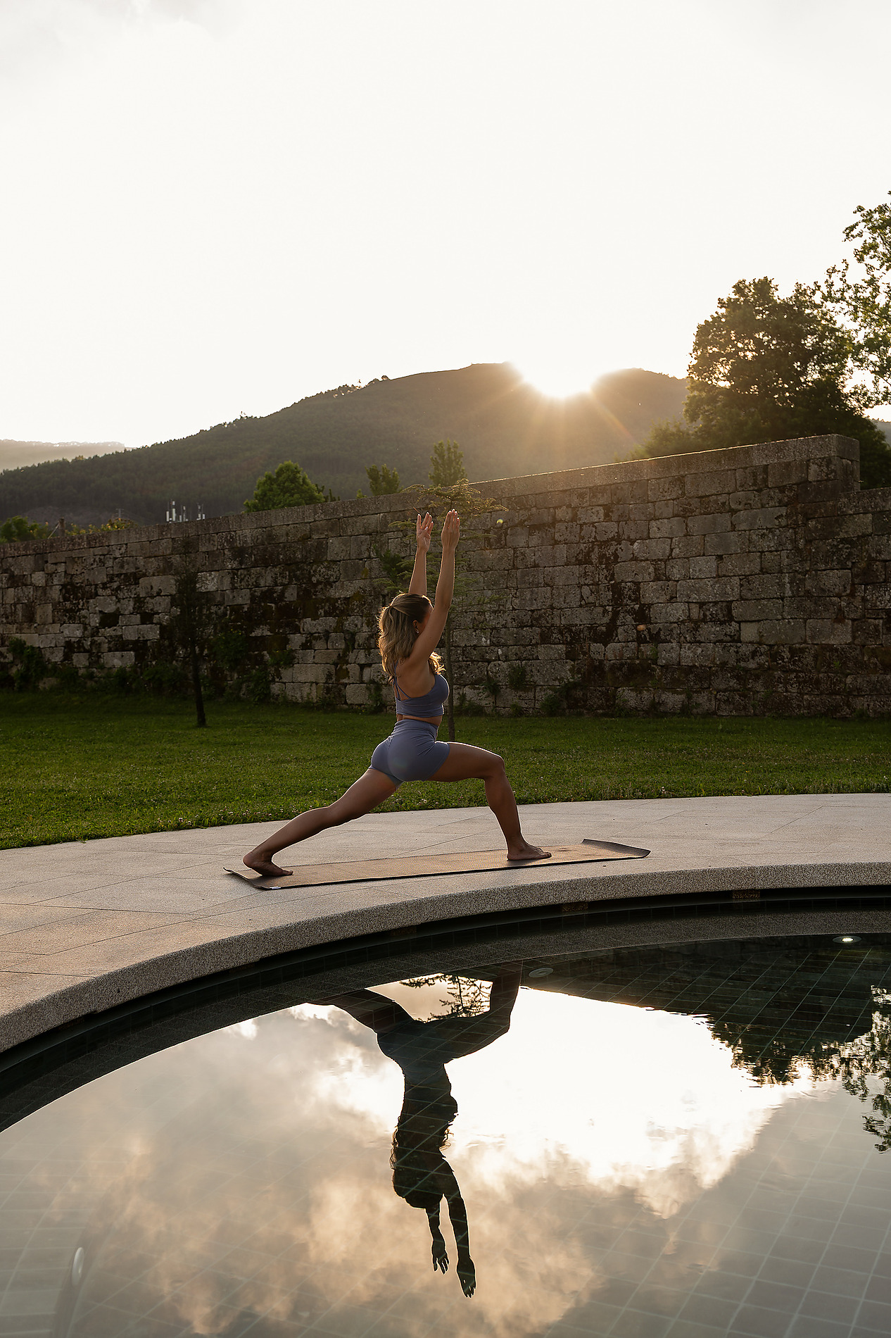 Mulher meditando em um tapete de yoga ao ar livre, com montanhas MS Collection: Mosteiro de Arouca | Arouca | Website Oficial ao fundo.