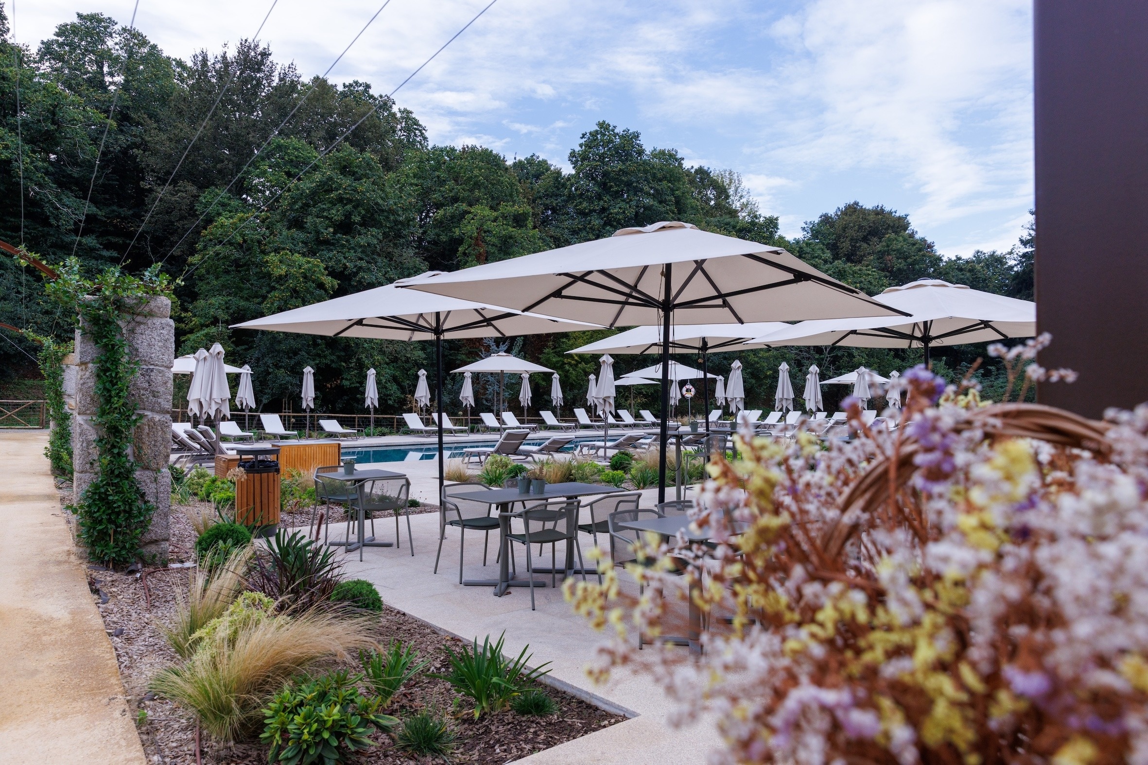 a patio area with tables and chairs under a pergola with umbrellas