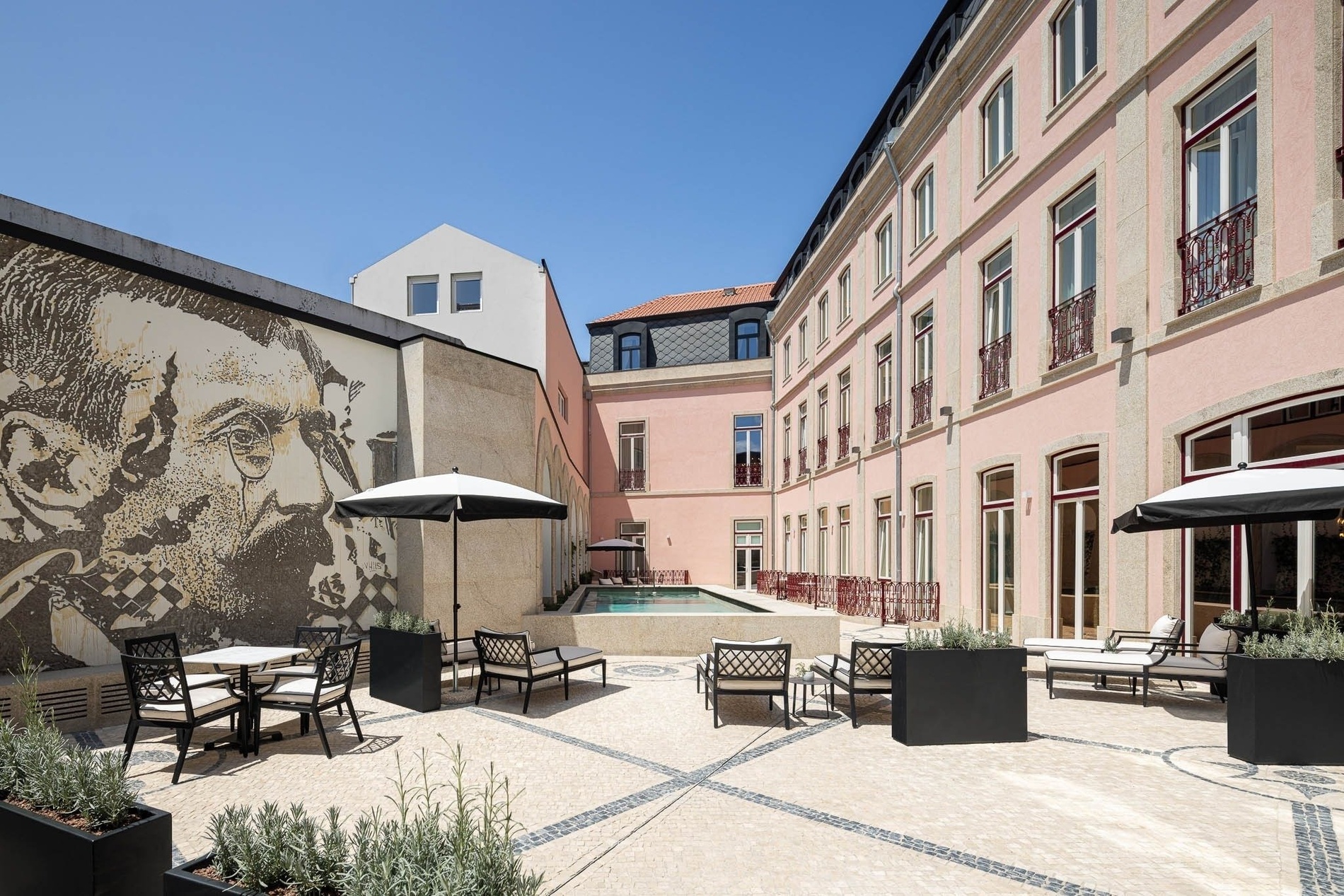 a courtyard with tables chairs and umbrellas in front of a large building