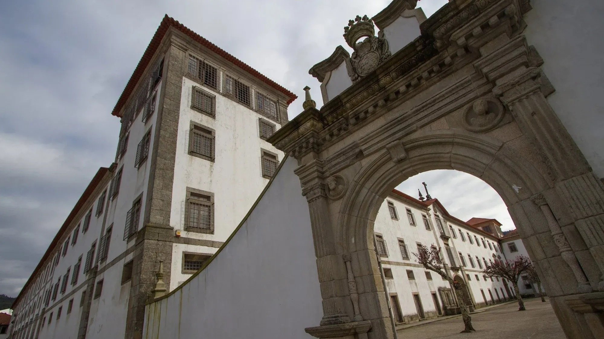 um prédio branco com um arco de pedra ao lado dele