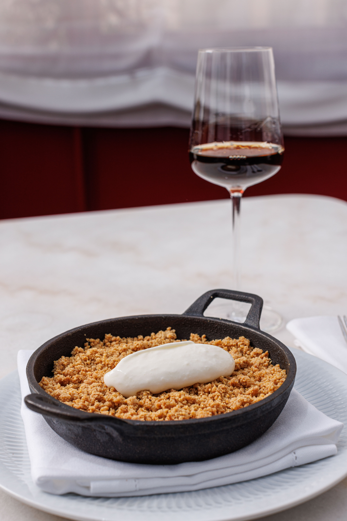 a pan of food sits on a plate next to a glass of wine