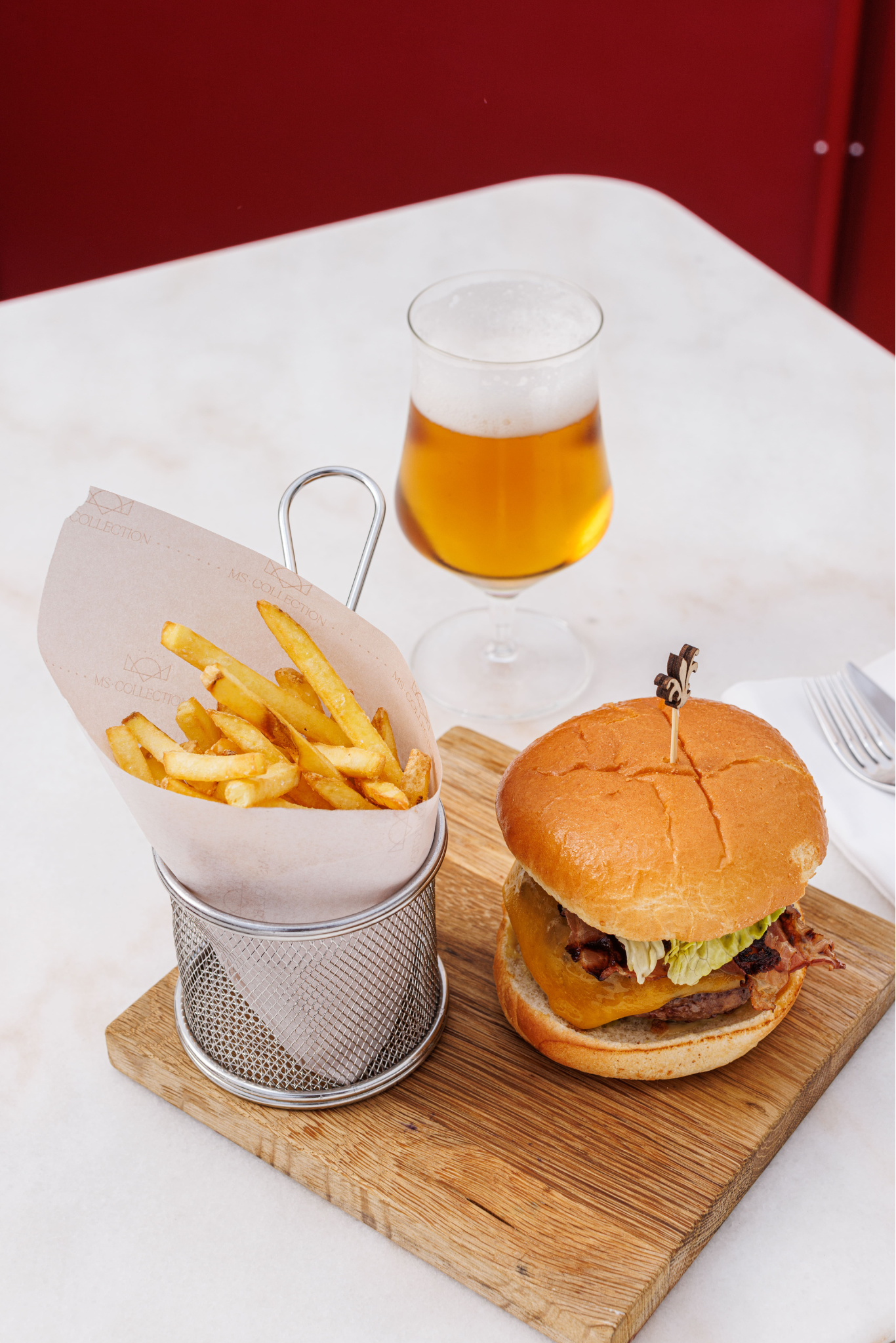 a basket of french fries next to a hamburger and a glass of beer