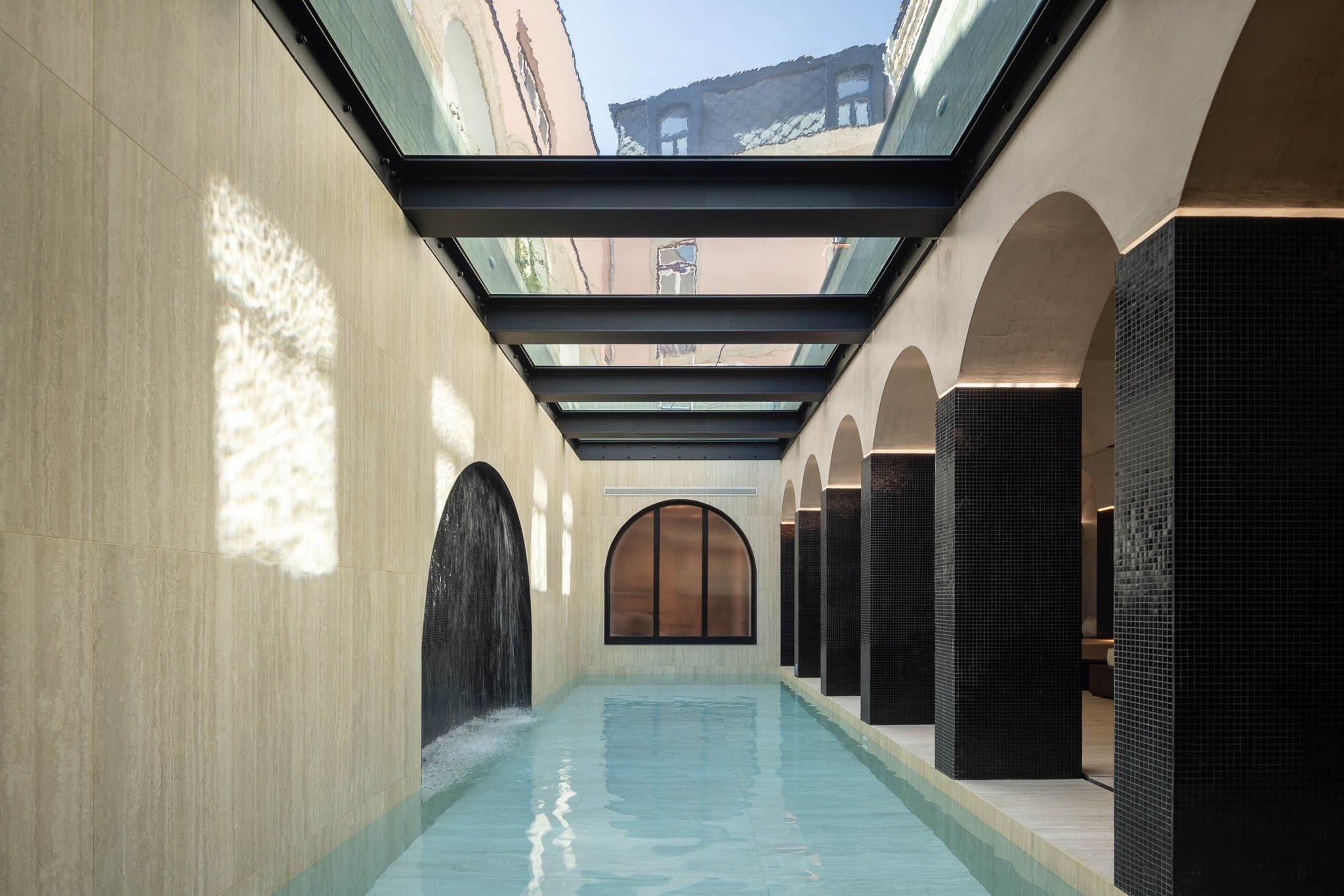 una piscina con techo de vidrio y columnas negras