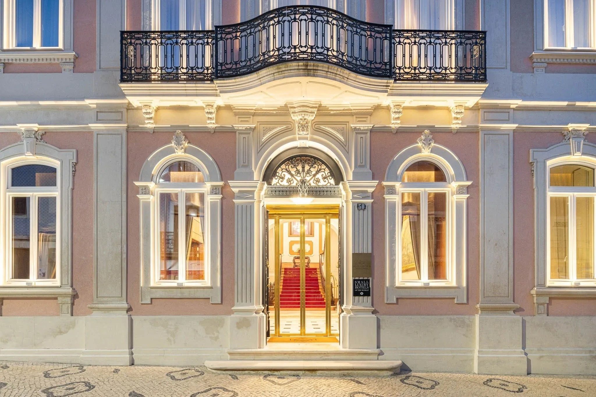 a pink building with a balcony and a red carpet