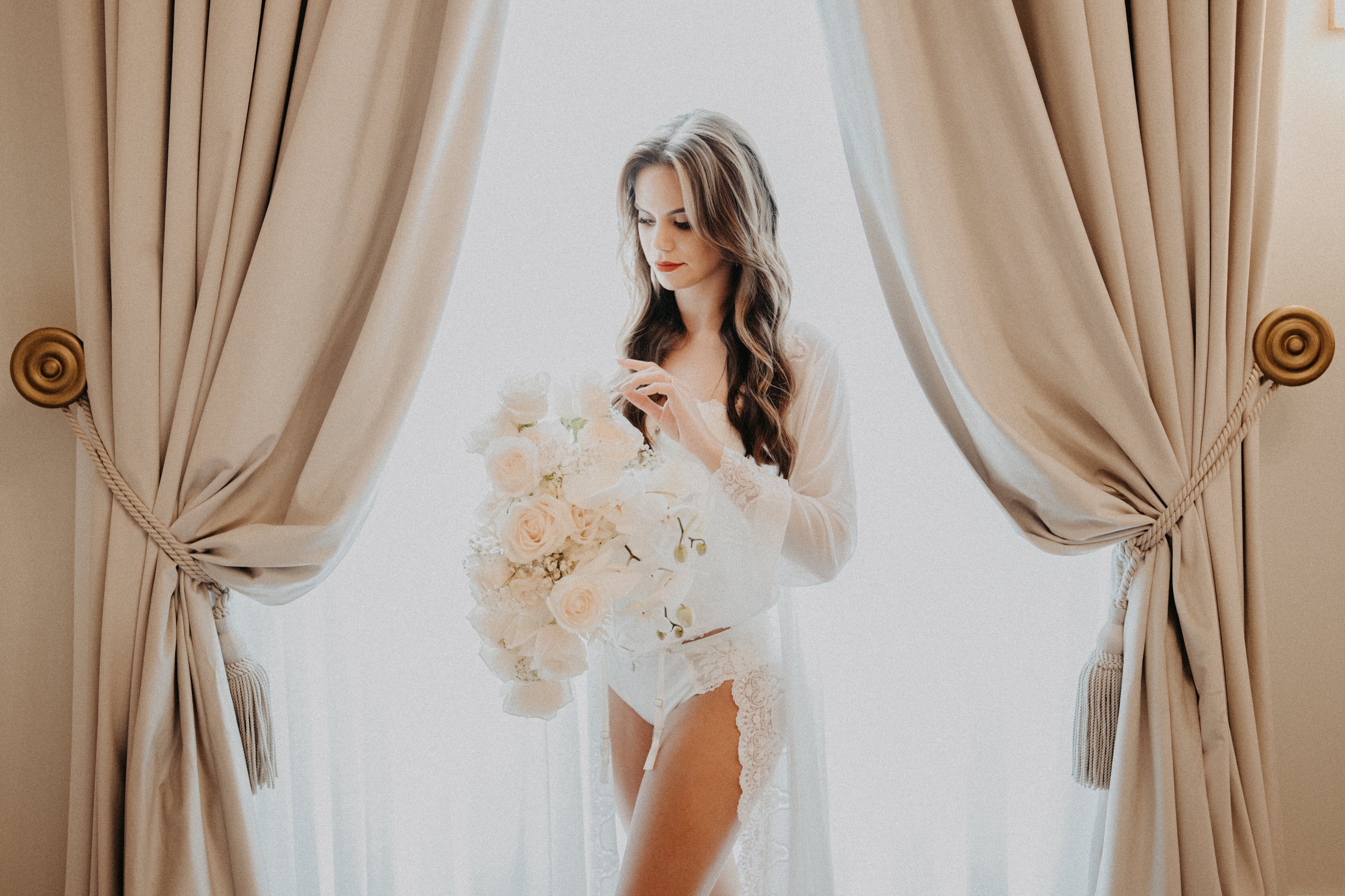 a woman in lingerie is holding a bouquet of white roses