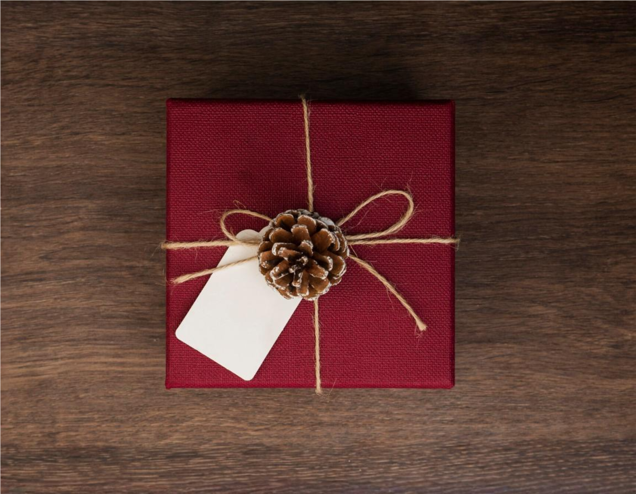 a red gift box with a pine cone and a tag