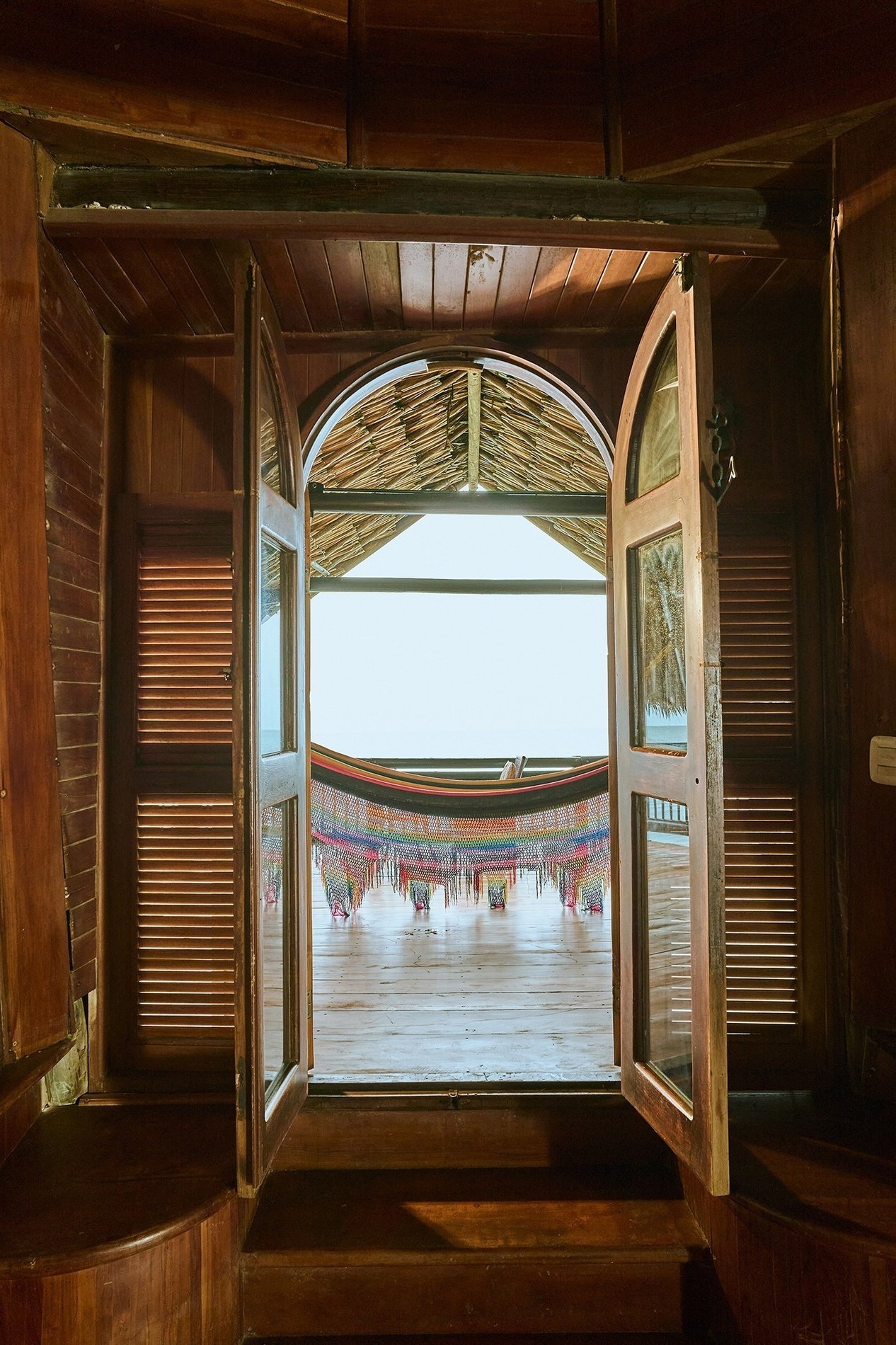 a hammock is visible through an open window in a wooden house