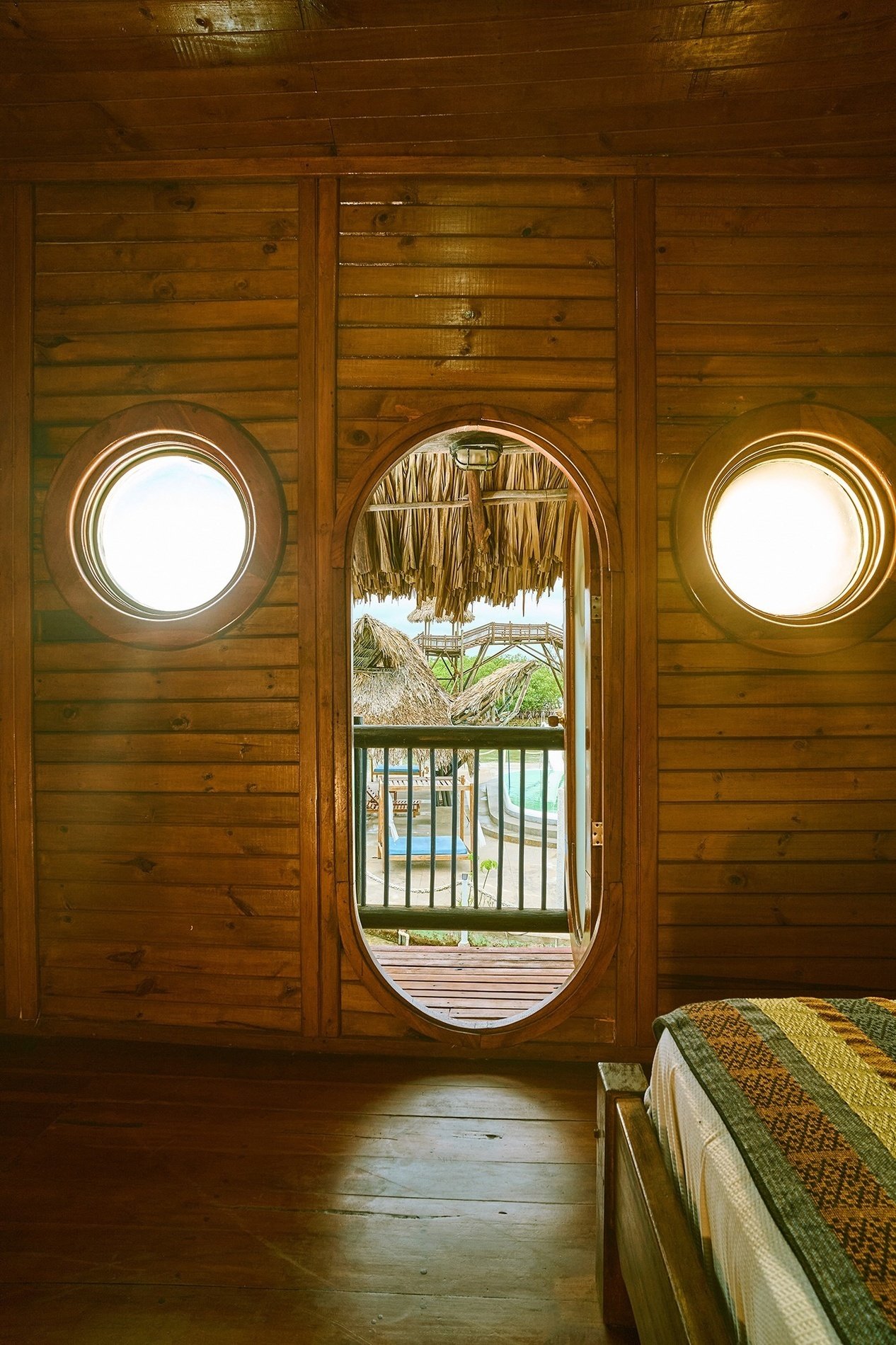 a bedroom with a round window looking out to a balcony