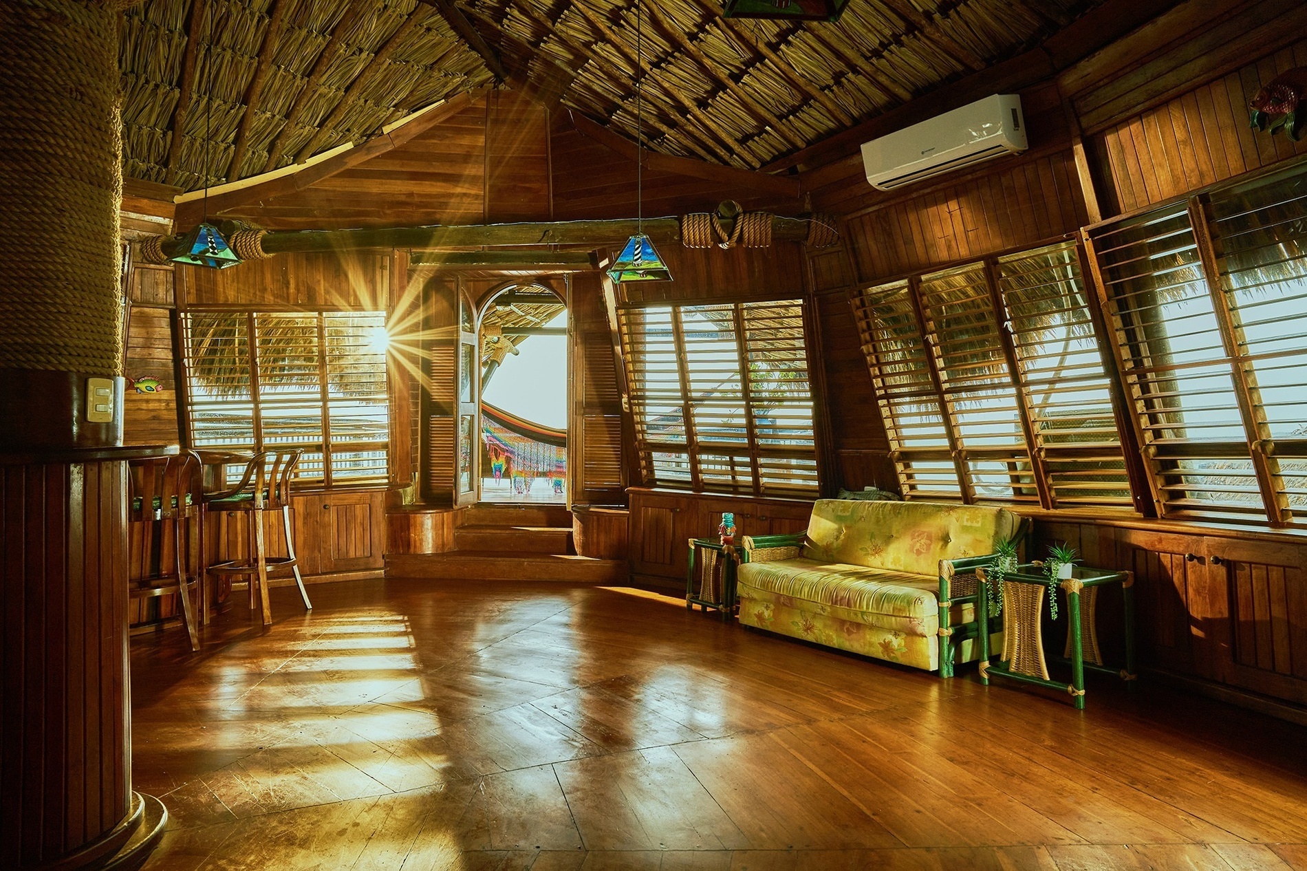 a wooden room with a couch and a thatched roof