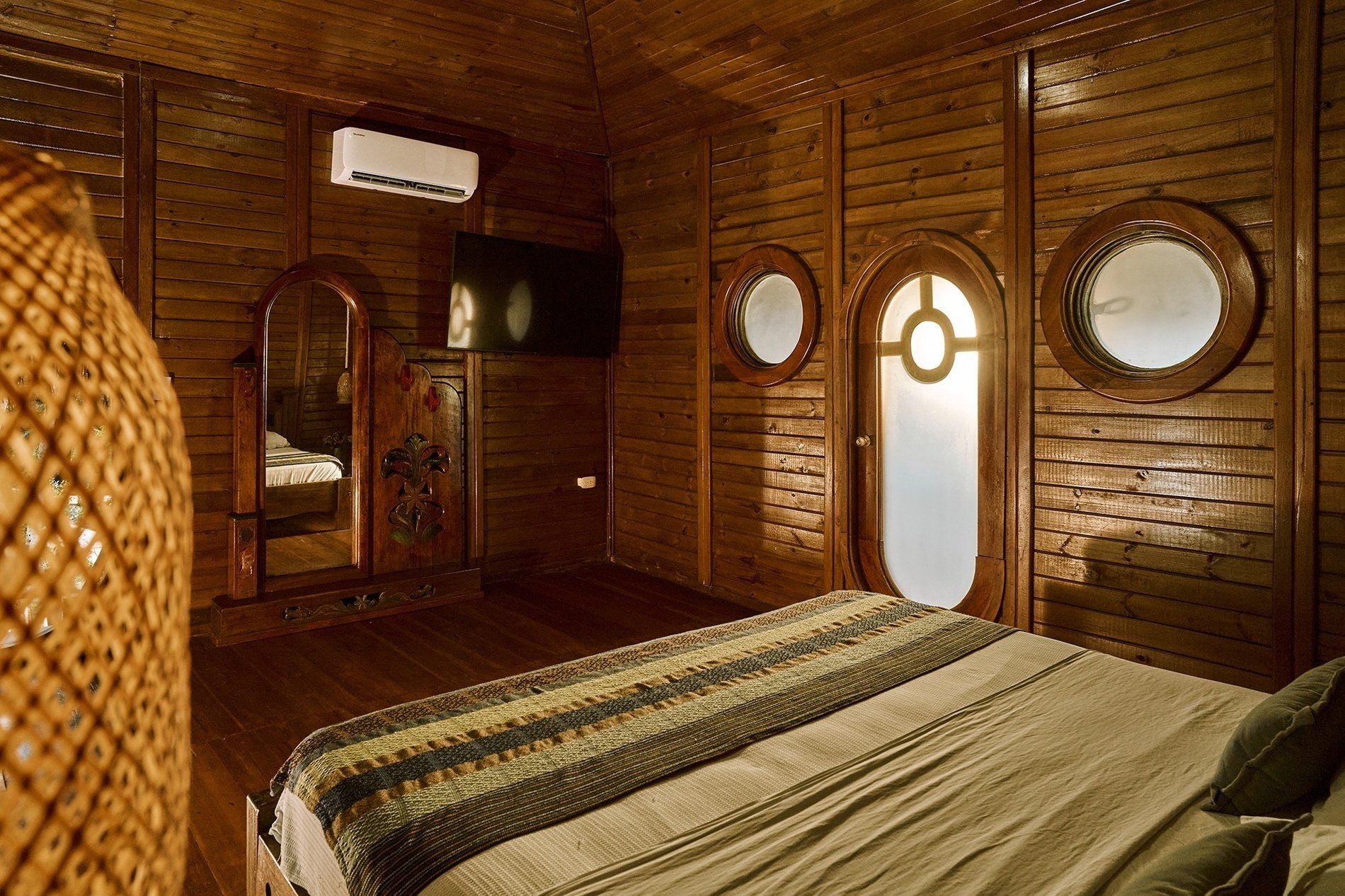 a wooden bedroom with a bed and a television