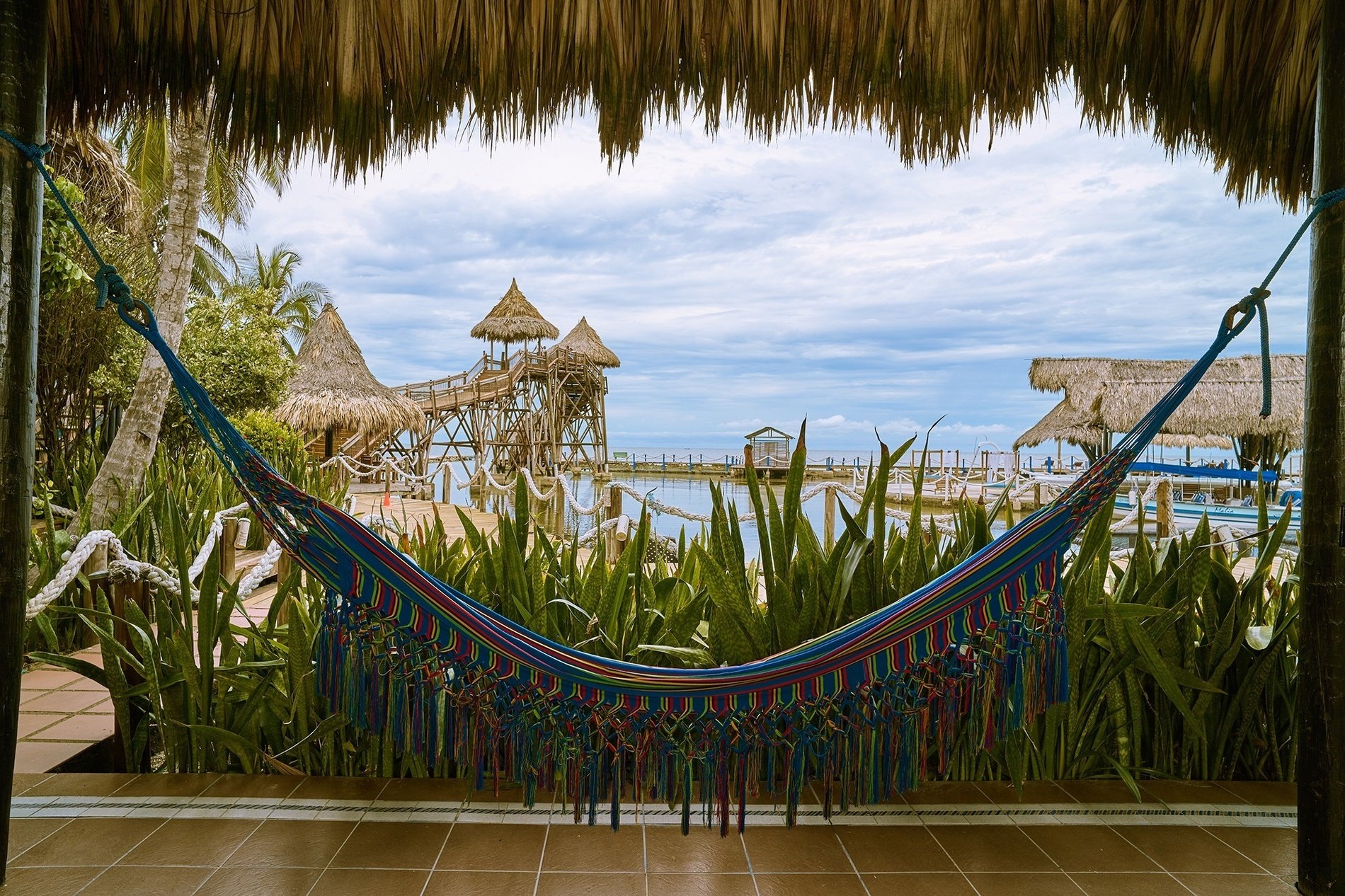 a colorful hammock is hanging in front of a thatched roof