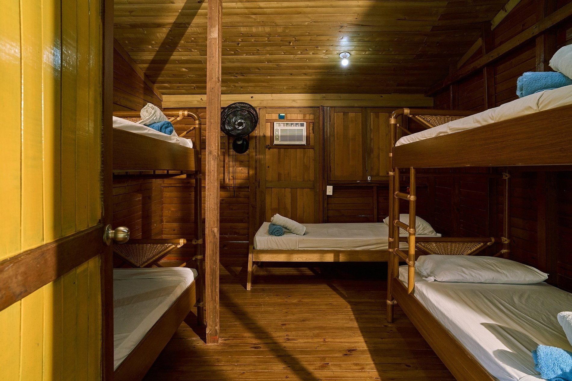 une chambre en bois avec des lits superposés et un ventilateur