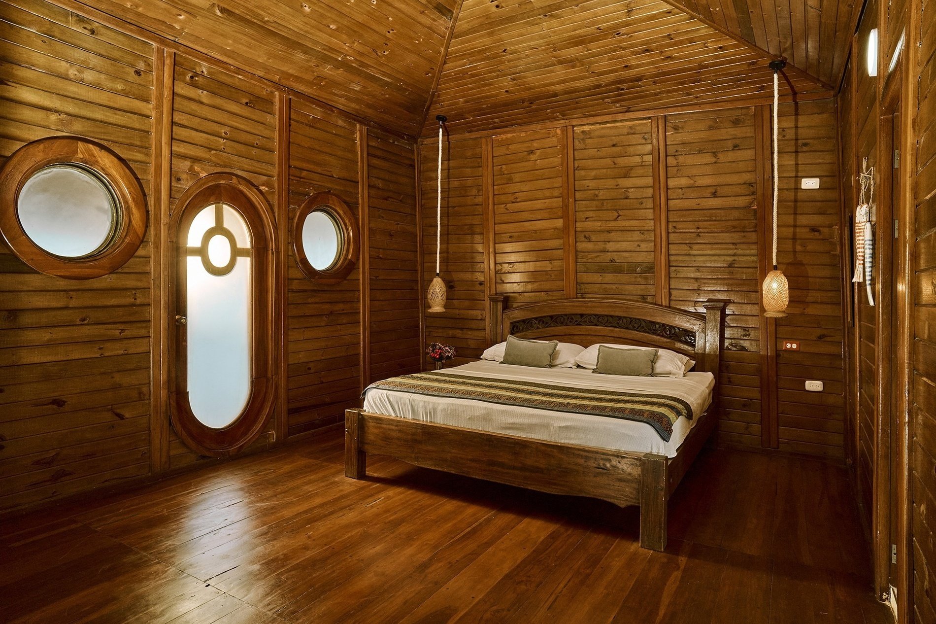 a wooden bedroom with a bed and two round windows