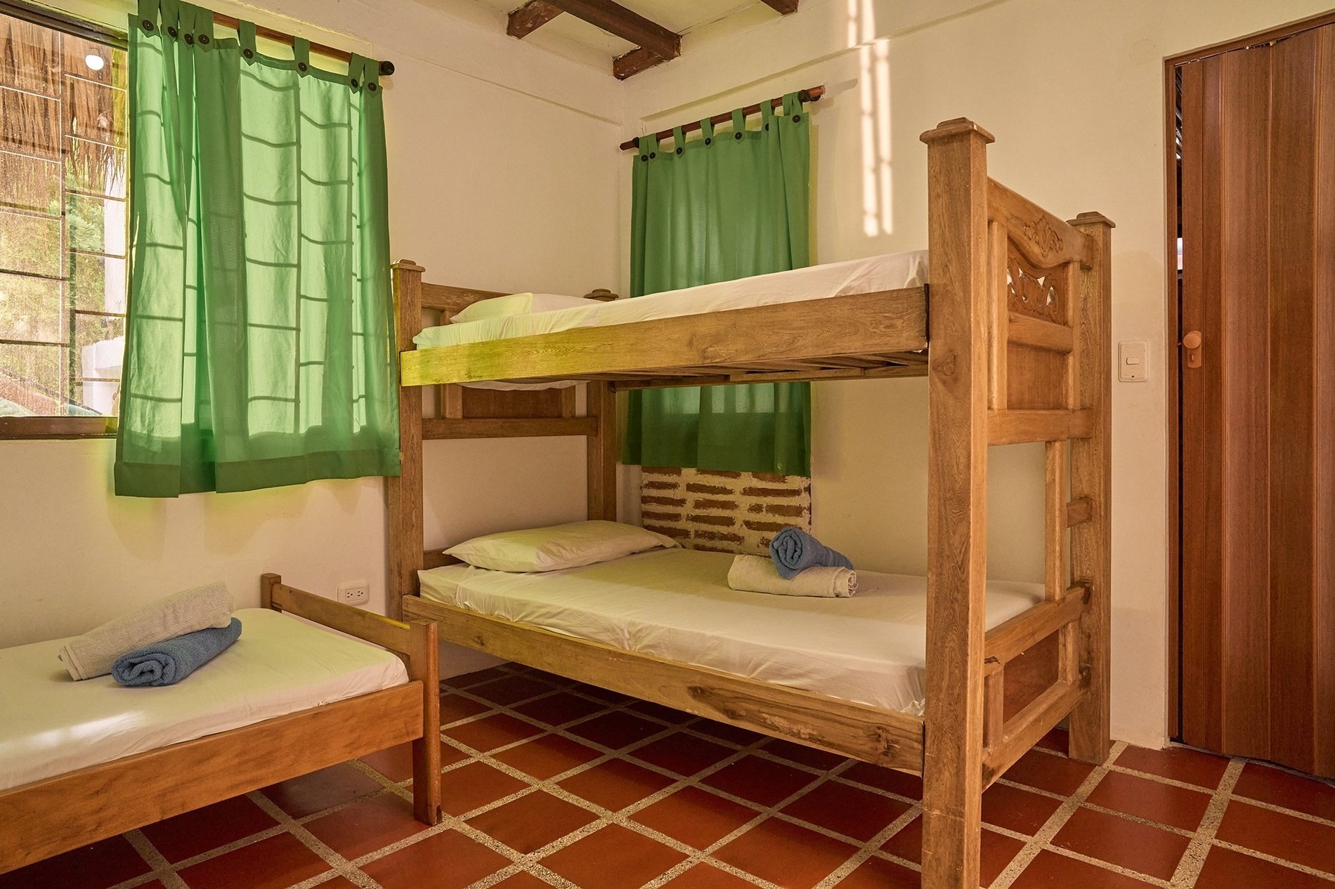 three bunk beds in a room with green curtains