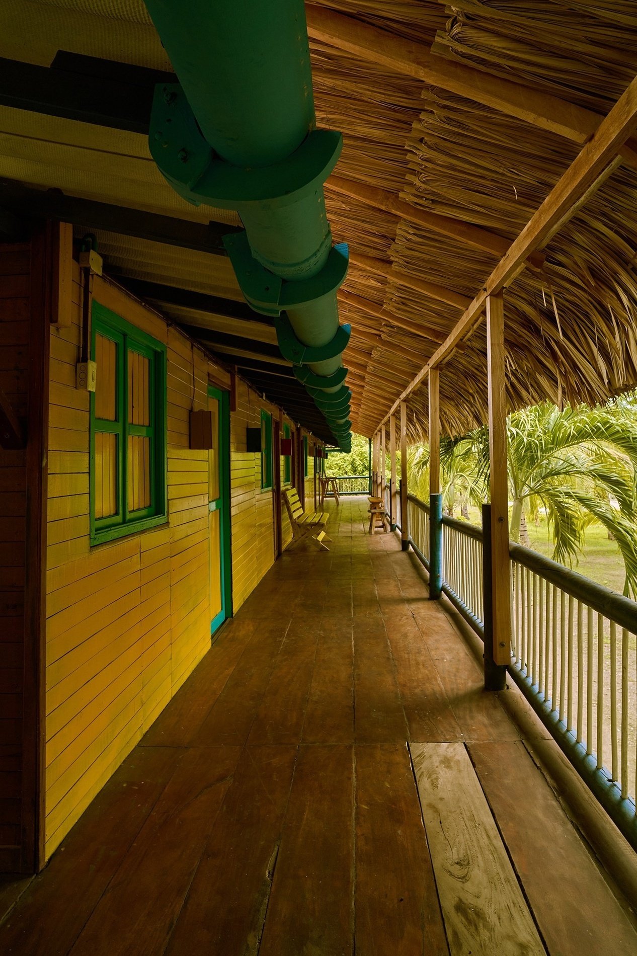 un largo pasillo de madera que conduce a un edificio amarillo y verde