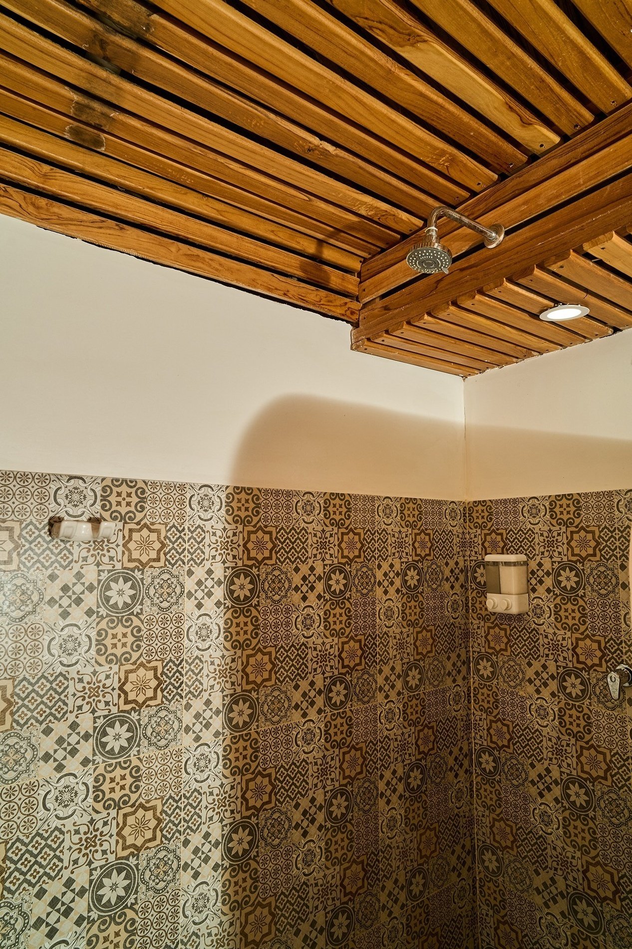 a bathroom with a wooden ceiling and a shower head