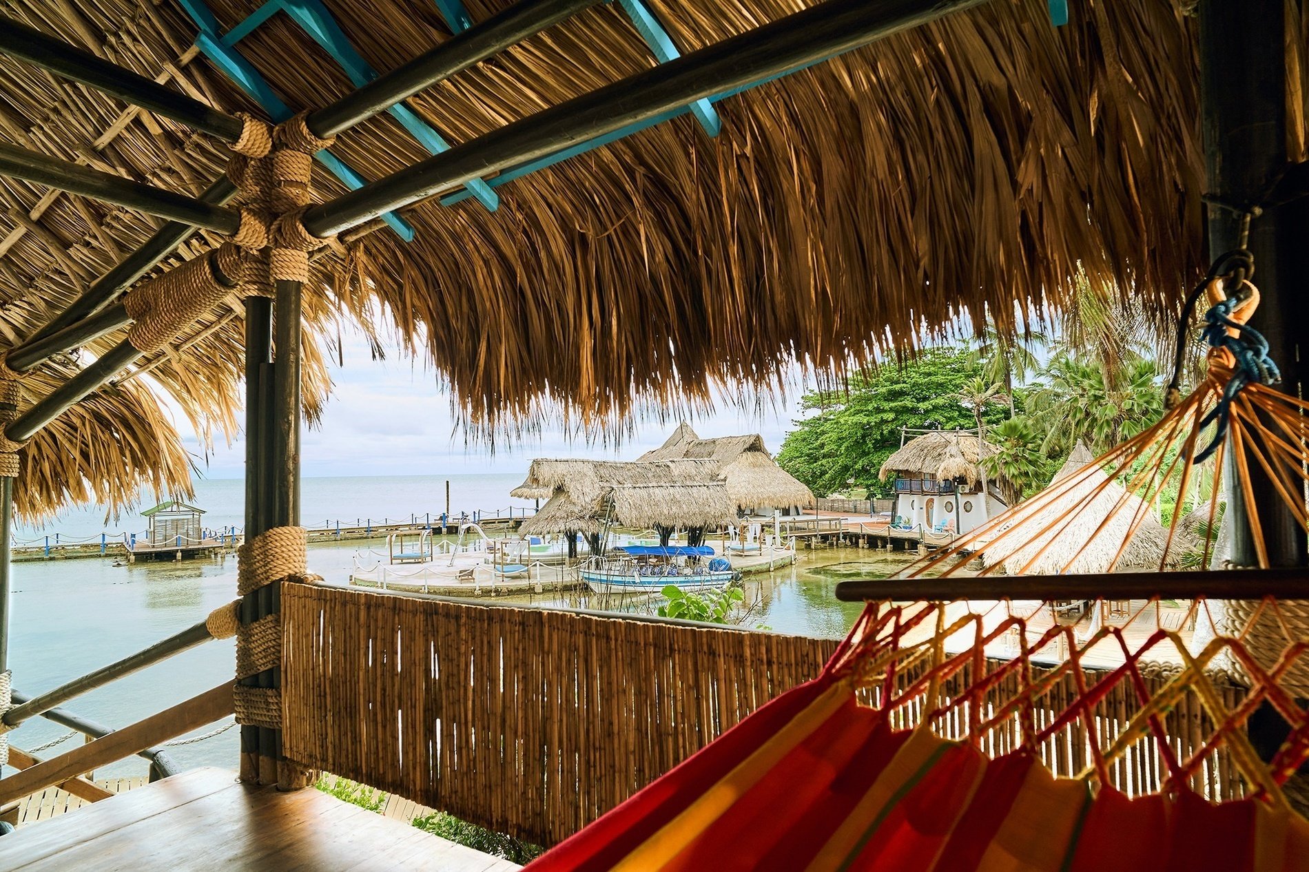 a hammock is hanging from the roof of a hut overlooking the ocean