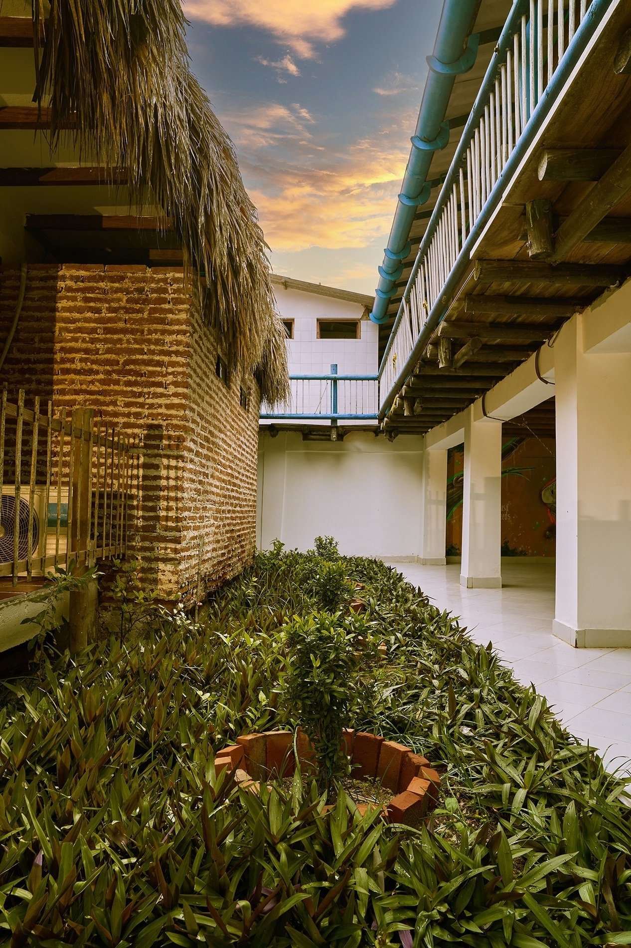 a brick building with a thatched roof sits next to a white building