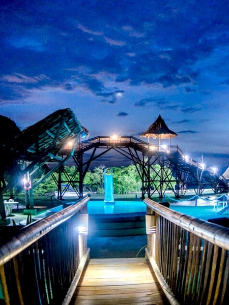 un puente de madera conduce a una piscina al atardecer