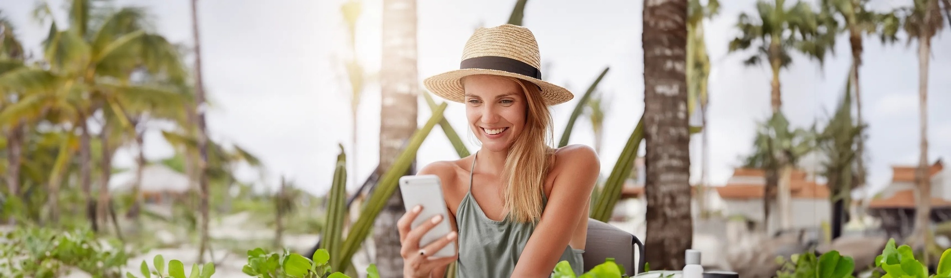 a woman wearing a straw hat is smiling while looking at her phone