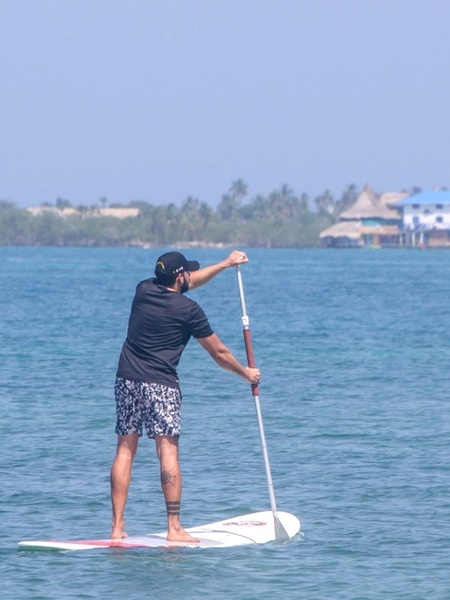 un hombre sostiene una paleta y una tabla de surf en el océano