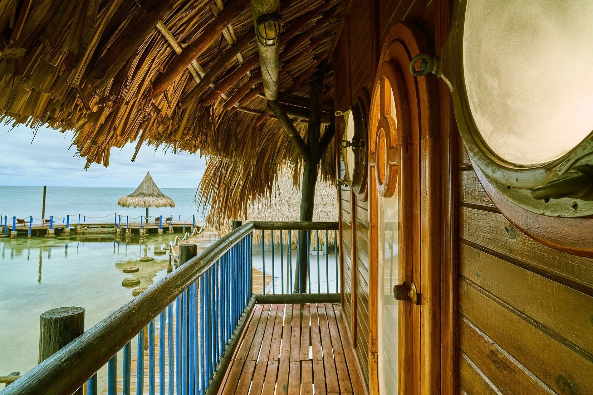 a balcony with a thatched roof overlooking the ocean