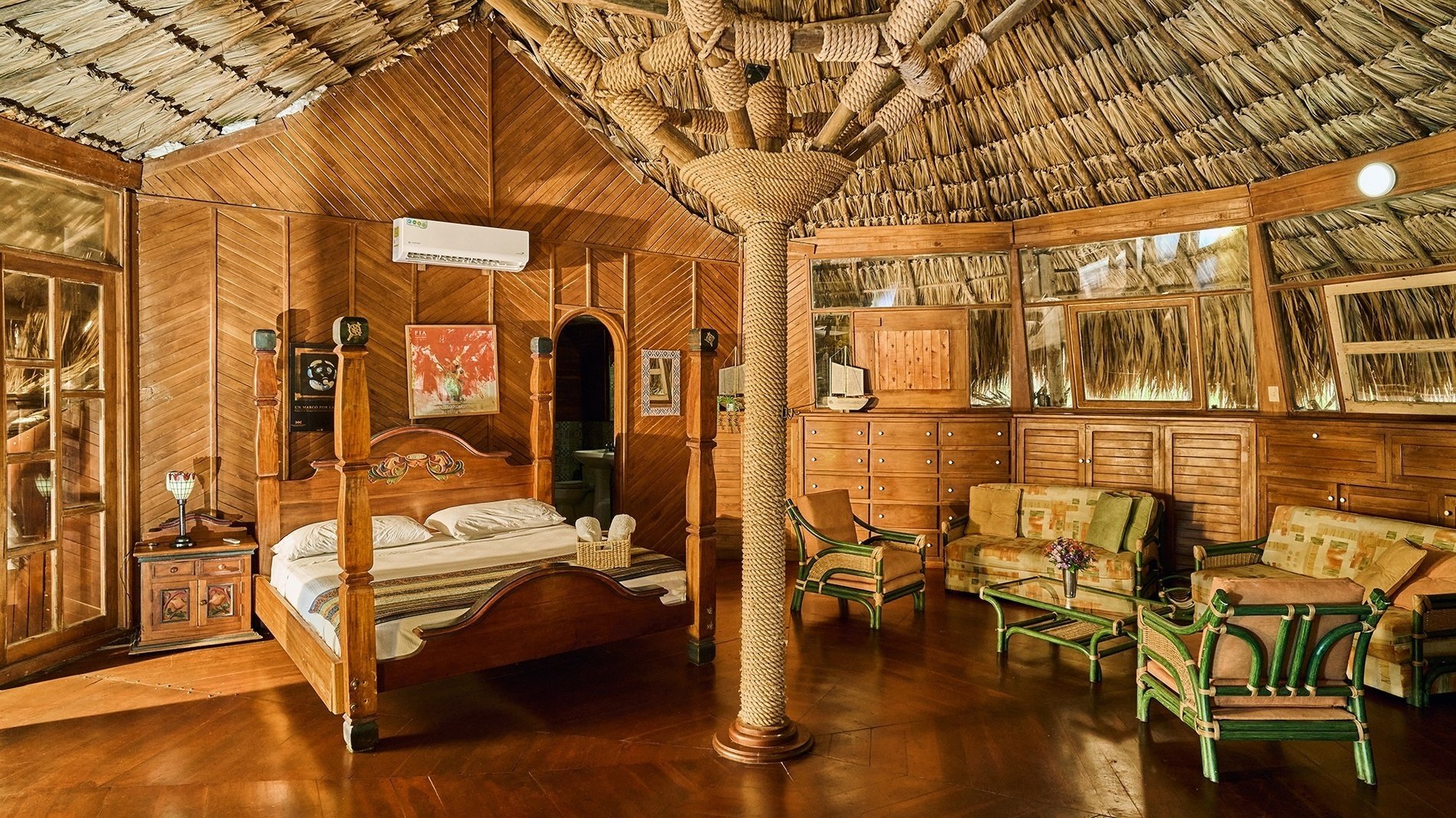 une chambre en bois avec un lit à baldaquin et un plafond de chaume