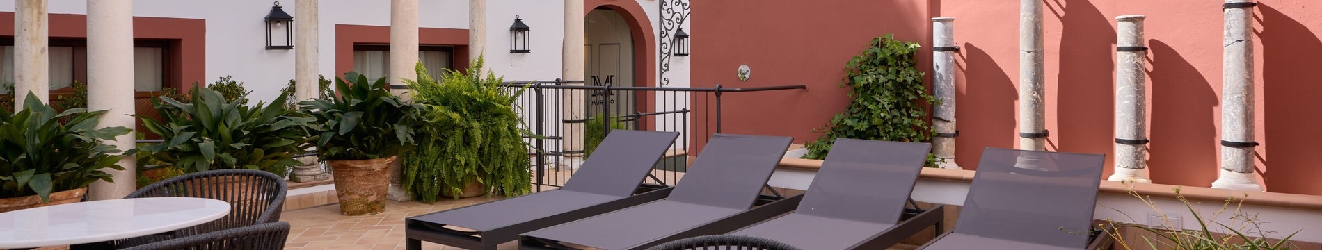 Interior courtyard of the Hotel Murillo Reinoso, with tables and sun loungers.
