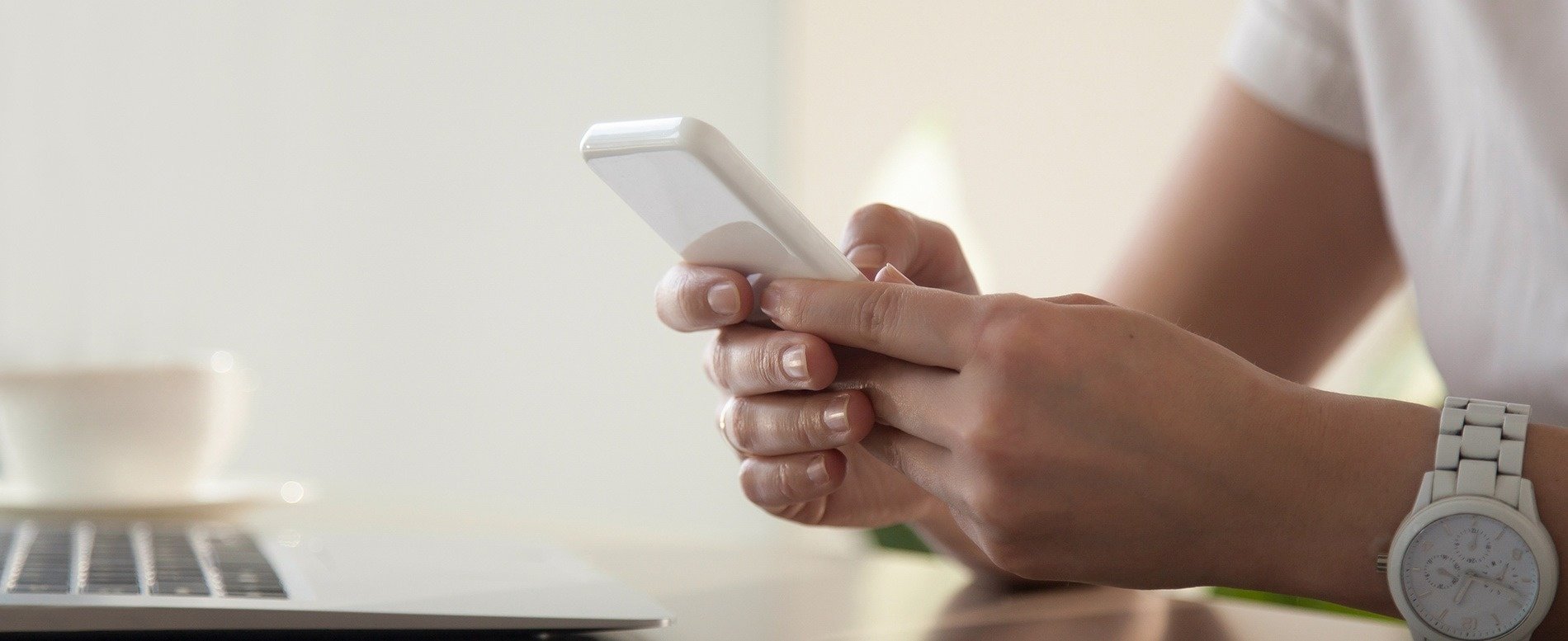 una mujer con un reloj blanco sostiene un teléfono inteligente