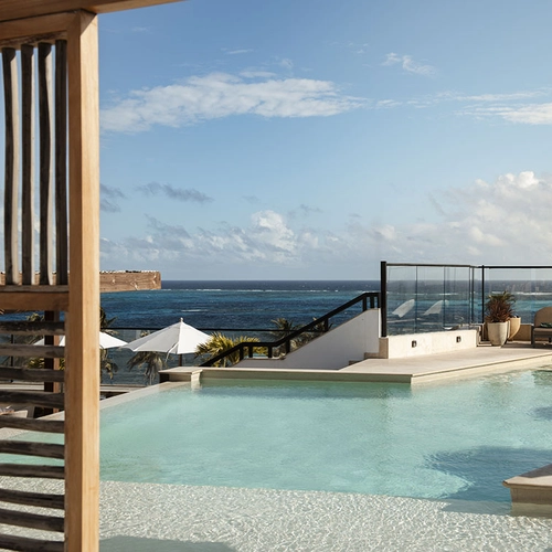 Piscina infinita con vista al mar Nattivo Collection Hotel, tumbonas y sombrillas.